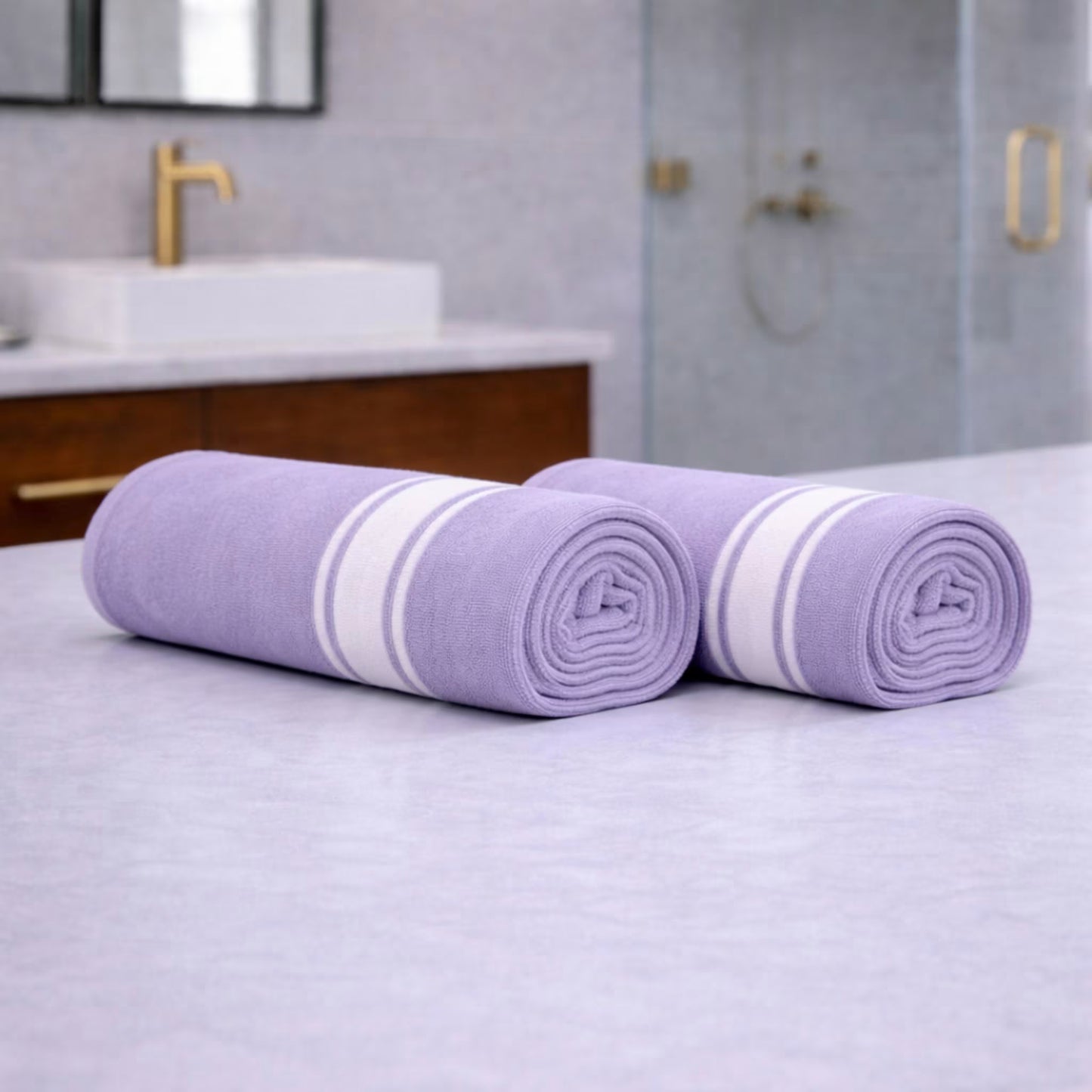 Two rolled purple bamboo bath towels side by side on a bathroom countertop (set of 2)